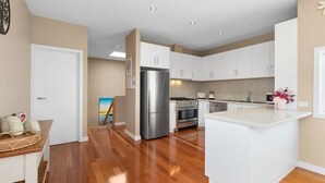 Une cuisine moderne avec des meubles blancs, des appareils en acier inoxydable et un plancher en bois.