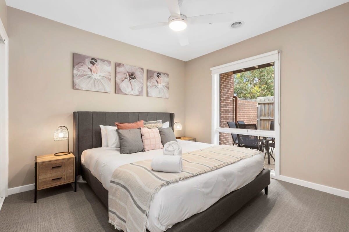 Quarto com uma cama grande, mesa de cabeceira, ventilador de teto e janela com vista para o exterior.