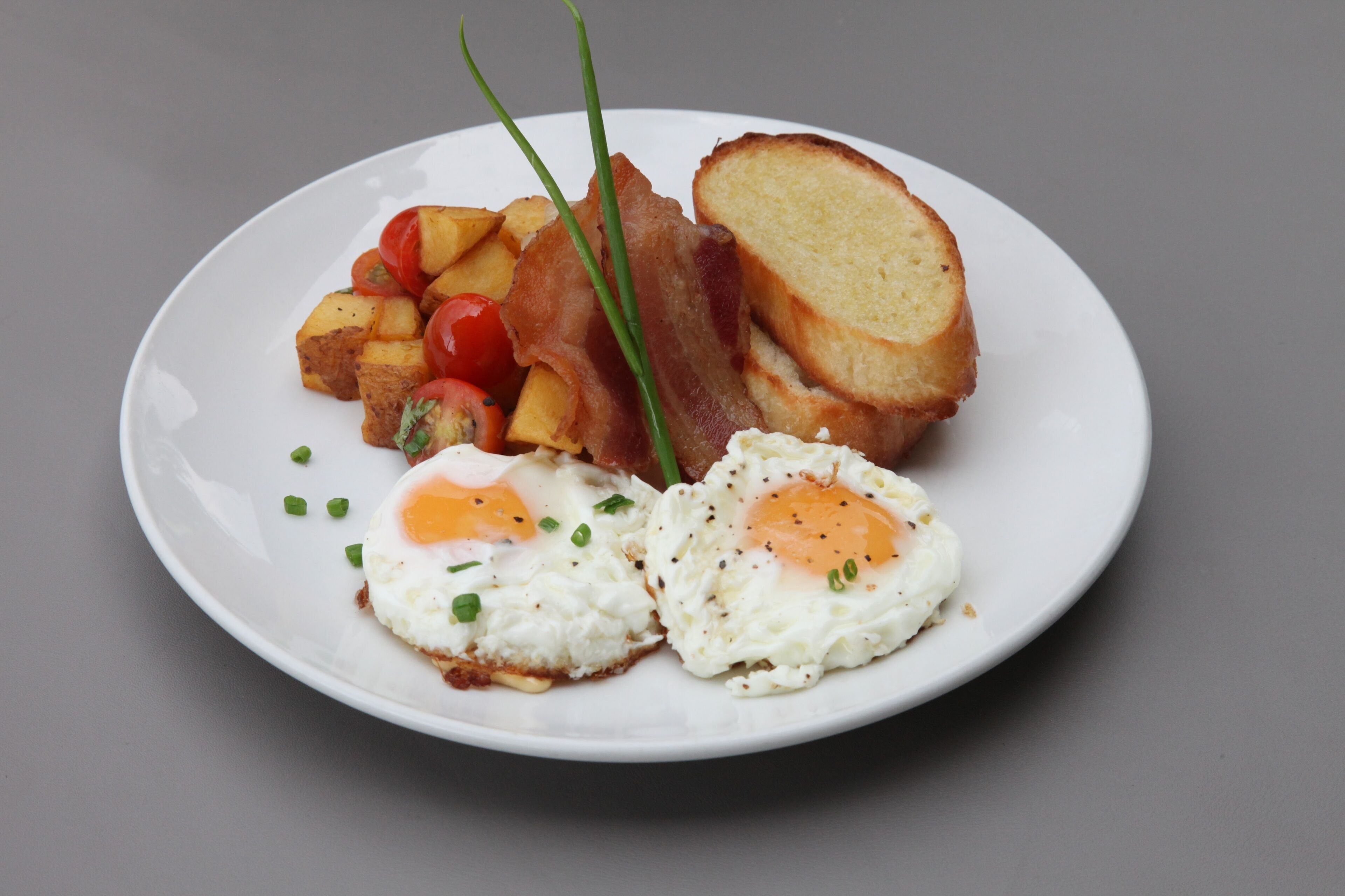 Une assiette avec des œufs, du bacon, des toasts et des pommes de terre.