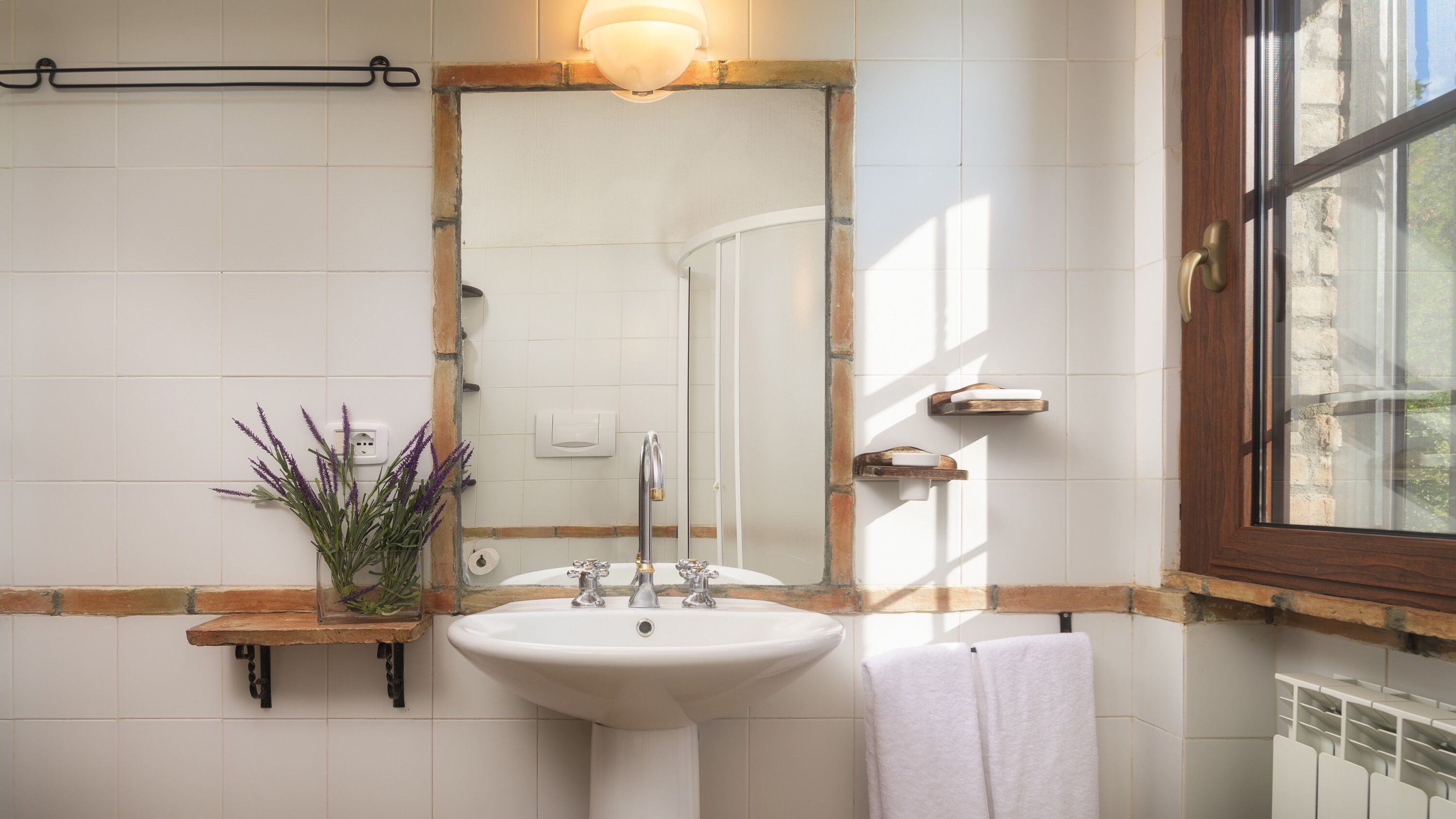Un baño con lavamanos blanco, espejo y ventana.