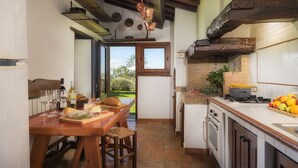 A kitchen with a wooden table, wine glasses, and a view of the outdoors. - Podere Caprarecce 8, Emma Villas (Baccinello)