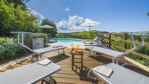 A wooden deck with lounge chairs, a pool, and a scenic view of hills and trees. - Podere Caprarecce 8, Emma Villas (Baccinello)
