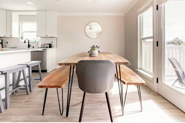 Una cucina moderna con mobili bianchi, un tavolo da pranzo in legno con panche e un'ampia finestra che offre vista sull'esterno.