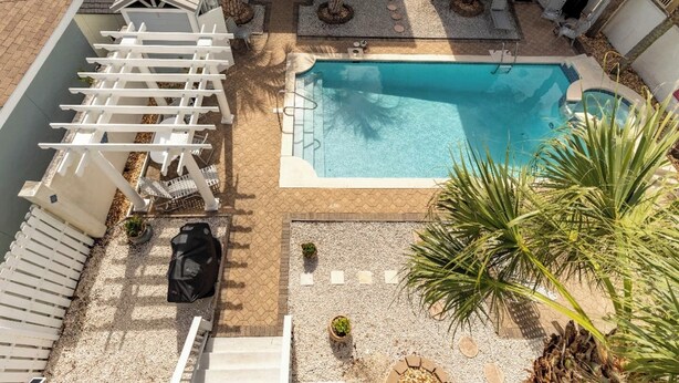 Ein Poolbereich auf dem Dach mit einer Pergola, Sitzgelegenheiten und Palmen.
