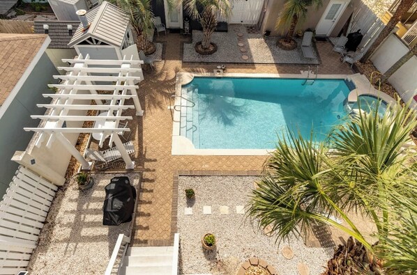 Ein Poolbereich auf dem Dach mit einer Pergola, Sitzgelegenheiten und Palmen.