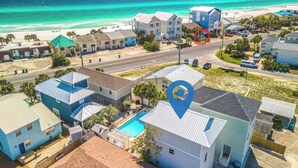 Zona residencial costera con casas, una piscina y una playa al fondo.