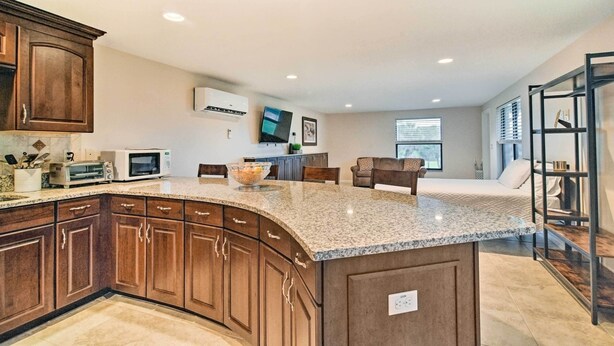 A modern kitchen with granite countertops, wooden cabinets, and a built-in microwave. - On-Site Pond: Sleek Largo Studio < 7 Mi to Beach! (Largo)