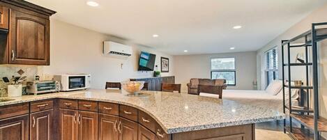A modern kitchen with granite countertops, wooden cabinets, and a built-in microwave.
