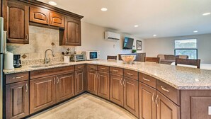 A modern kitchen with dark wood cabinets, granite countertops, and a built-in microwave. - On-Site Pond: Sleek Largo Studio < 7 Mi to Beach! (Largo)