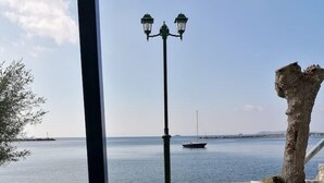 A table with two glasses of white wine, a street lamp, and a view of the sea with boats. - "Eothinos" Sea front Studio (Glossa Skopelos Island,)