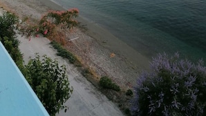Eine ruhige Küstenansicht mit freiem Blick auf das Meer, ein kleines Boot vor der Küste verankert und ein Felsenmole in der Ferne.