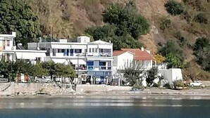 Ein Küstenwohngebiet mit mehrstöckigen Gebäuden, freiem Blick auf das Meer und einer Hügelkulisse im Hintergrund.