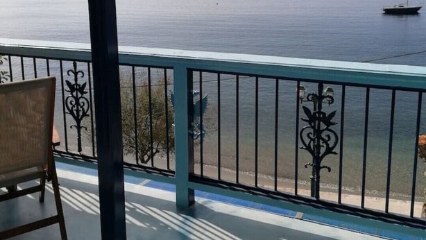 Un balcon avec vue sur la mer, une chaise et une rambarde.