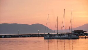 Un port de plaisance où plusieurs voiliers sont amarrés au coucher du soleil.