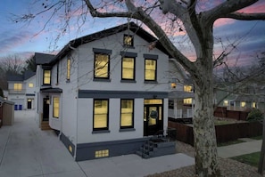 A two-story house with a front porch, a visible staircase, and a well-lit front door.