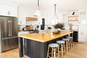 A modern kitchen with a central island, stainless steel appliances, and bar stools.