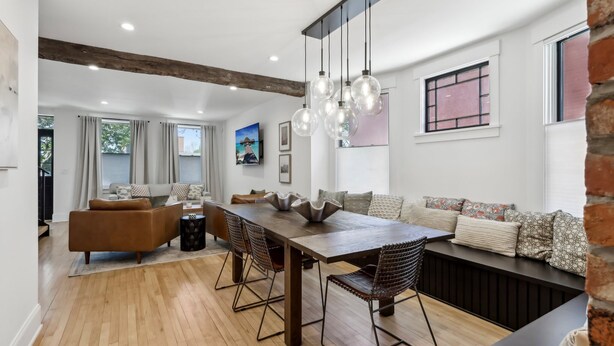 Un comedor moderno con una mesa de madera, sillas de metal y una lámpara colgante.