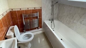 A bathroom with a skylight, a bathtub, and a toilet. - 4 bed Townhouse- Free parking (Greater London)