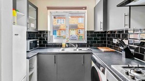 A modern kitchen with a built-in stove, a sink, and a window overlooking a residential area.
