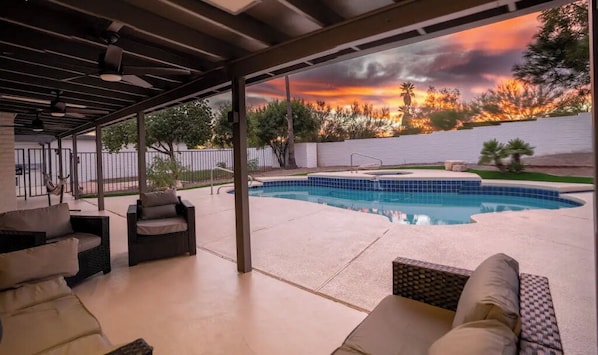 Relax by the pool surrounded by lush trees and comfortable seating.