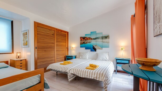 Ein Schlafzimmer mit zwei Betten, einem Holzschrank, einem Gemälde und einem Tisch mit einer Schüssel.