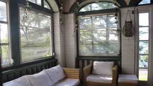 A sunroom with a white sofa, wicker chairs, and a glass coffee table. - Lakeview Historic Home Guest Rave: Delicious Breakfast  (Wisconsin Dells)