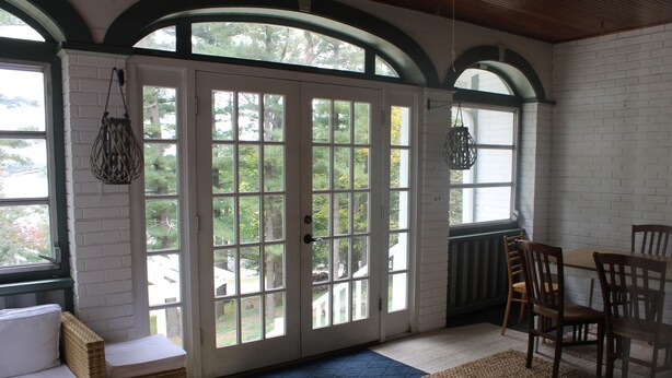 A room with a large sliding glass door leading to a patio, wicker furniture, and a dining table with chairs. - Lakeview Historic Home Guest Rave: Delicious Breakfast  (Wisconsin Dells)