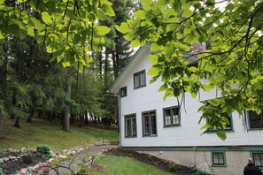 A white house with green trim, surrounded by trees and a stone pathway. - Lakeview Historic Home Guest Rave: Delicious Breakfast  (Wisconsin Dells)