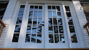 A white double door with multiple panes, set within a building with white siding and dark trim. - Lakeview Historic Home Guest Rave: Delicious Breakfast  (Wisconsin Dells)