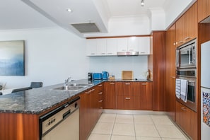A modern kitchen with wooden cabinets, a granite countertop, and stainless steel appliances.