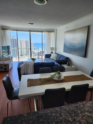 Enjoy a city and sea view from the comfort of this stylish living room, featuring a sofa, dining table, and TV.
