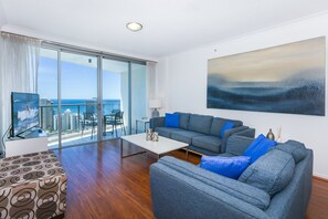 Enjoy a panoramic view of the city and ocean from this stylish living room with a floor-to-ceiling glass window.