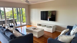 Relax in this stylish living room with a large flat-screen TV, comfortable sofa, and sliding glass door leading to an outdoor patio.
