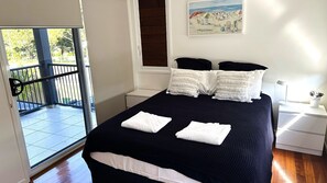 Relax in a serene bedroom with a large bed, bedside table, and a potted plant, plus a sliding door to a balcony with a view.