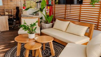 A modern living room with a sofa, two round wooden tables, and potted plants.