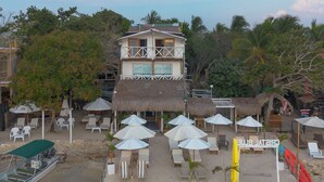 A beachfront hotel with a two-story building, outdoor seating area with umbrellas, and a boat dock. - Cristal Blue Baru (Cartagena)