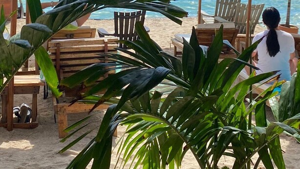 A beachside seating area with wooden chairs and umbrellas, overlooking the sea. - Cristal Blue Baru (Cartagena)