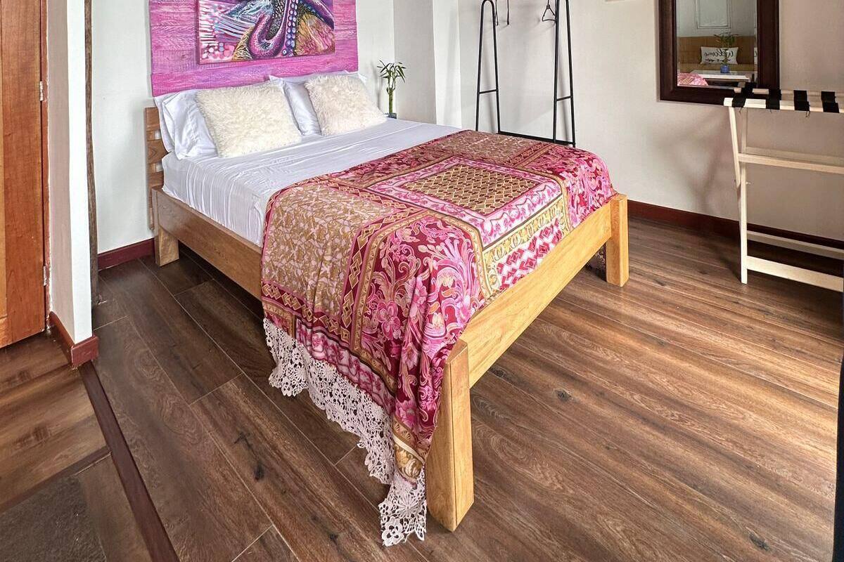 A bedroom with a wooden bed, a large painting, a hanging light fixture, and a mirror on the wall.
