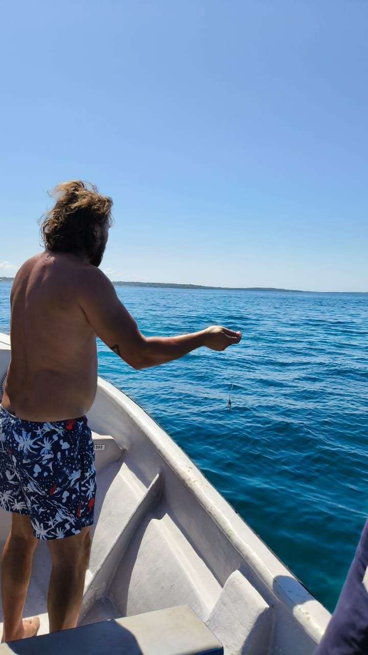 A person in a boat wearing patterned swim trunks.