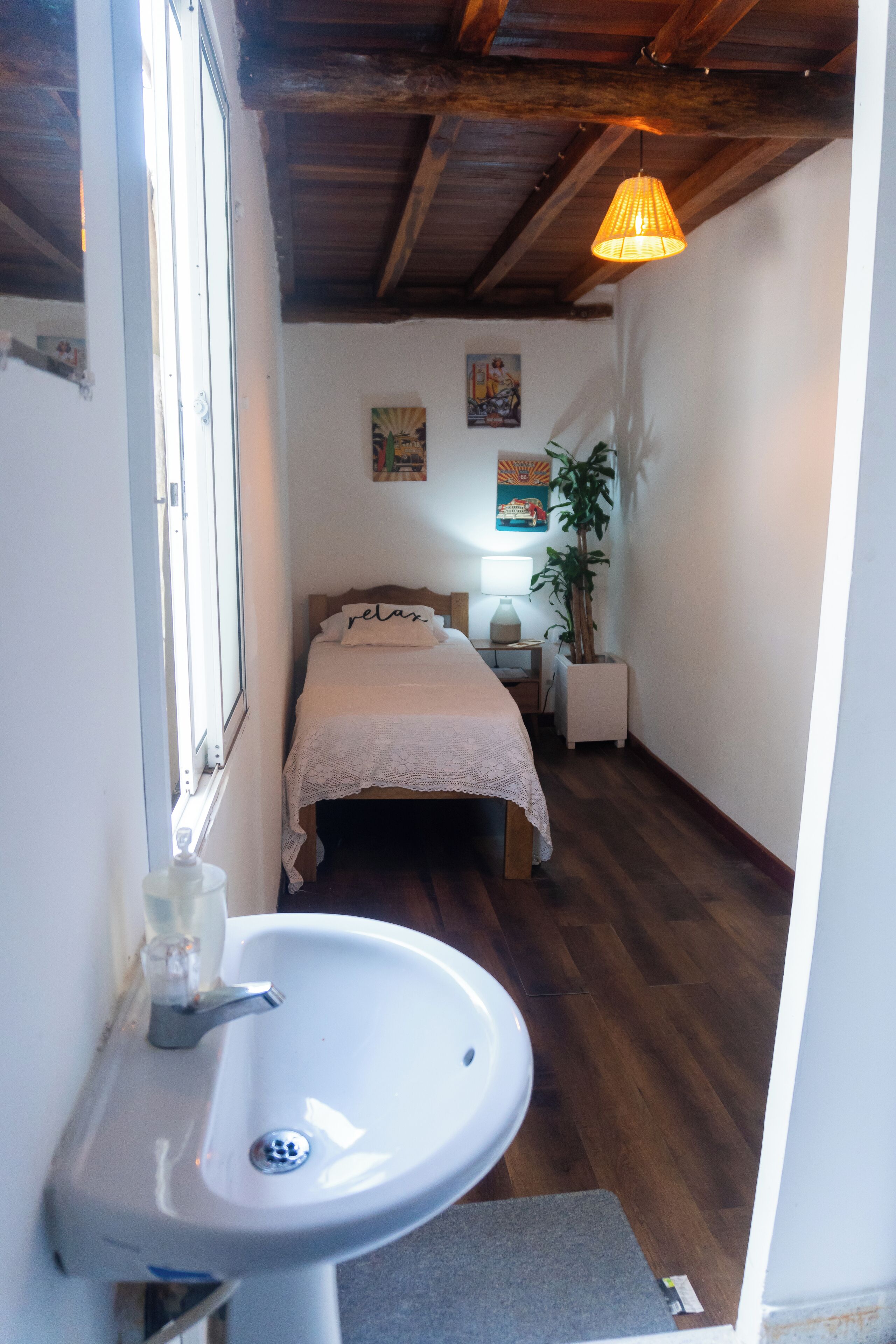 Une petite pièce comprenant un lit, une table de chevet, une lampe et un luminaire suspendu.