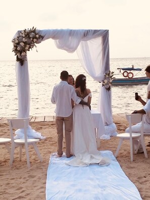 A beach wedding ceremony with a white arch and floral decorations. - Cristal Blue Baru (Cartagena)