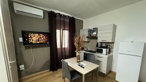 Eine kompakte Küche mit Essbereich, einem Flachbildfernseher und einem weißen Kühlschrank.