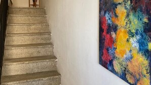 Eine Treppe mit steiniger Oberfläche führt zu einer Zwischenebene mit einer Vase und einem kleinen Tisch.