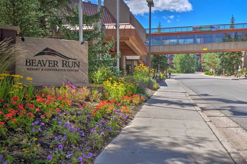 A sign for Beaver Run Resort & Conference Center with a pedestrian bridge in the background.