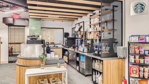 A modern coffee shop interior with a coffee machine, shelves stocked with snacks, and a Starbucks logo on the wall. - Cozy Ski-In/Out Studio In Building 4 | Kitchen | Hot Tubs, Dog Friendly (Breckenridge)