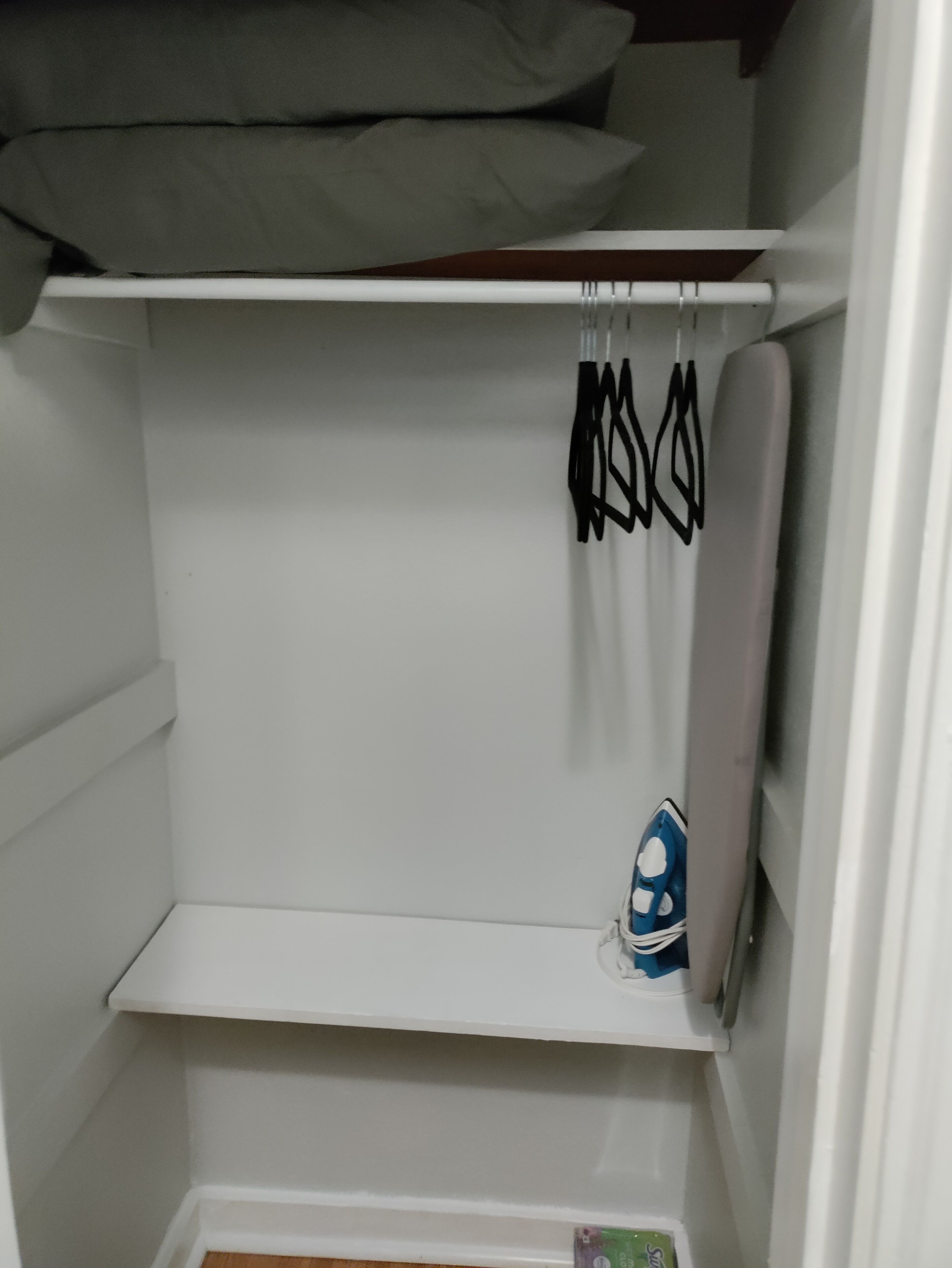 Une armoire blanche avec des étagères et une tringle pour suspendre les vêtements.