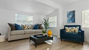 Ein Wohnzimmer mit Sofa, Sessel, Couchtisch und einer Pflanze.