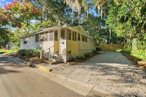 A single-story mobile home with a porch, a mailbox, and a gravel driveway.