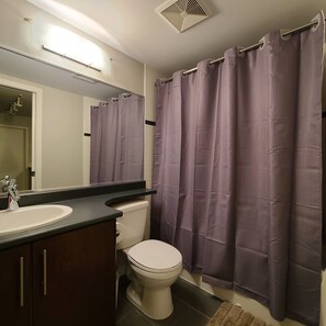 Een bad/douchecombinatie, een haardroger, handdoeken, zeep