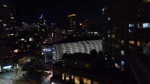 A nighttime cityscape with a prominent curved building with glass panels, surrounded by high-rise buildings with illuminated windows. - Charming Dwelling Downtown Vancouver (Vancouver)